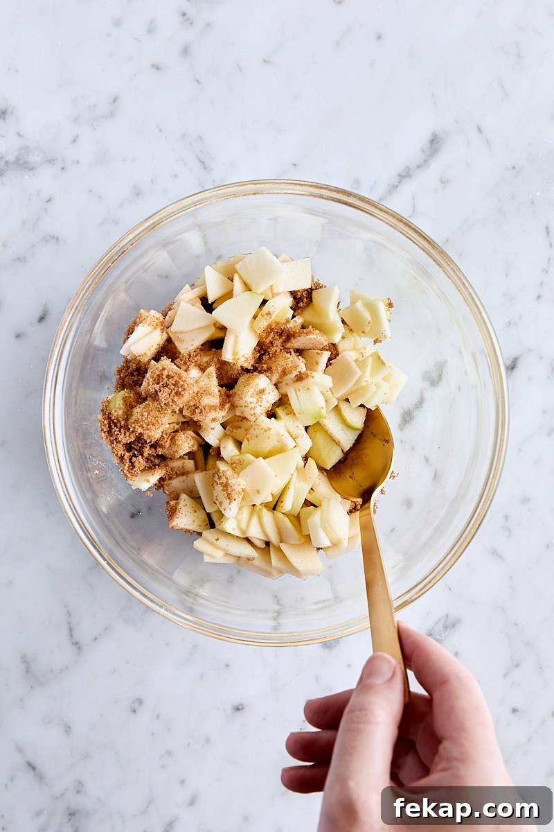 Tossing chopped apples with dark brown sugar in a small bowl