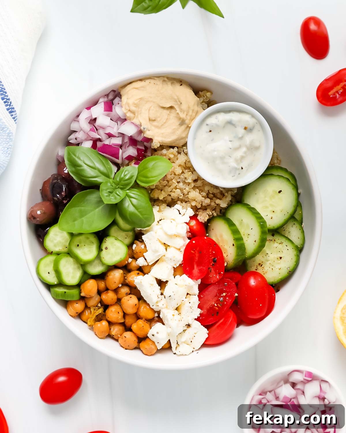 Greek Quinoa Bowl Recipe with Feta, Cucumber and Olives 4 A bowl of greek salad with cucumbers, tomatoes, and chickpeas.