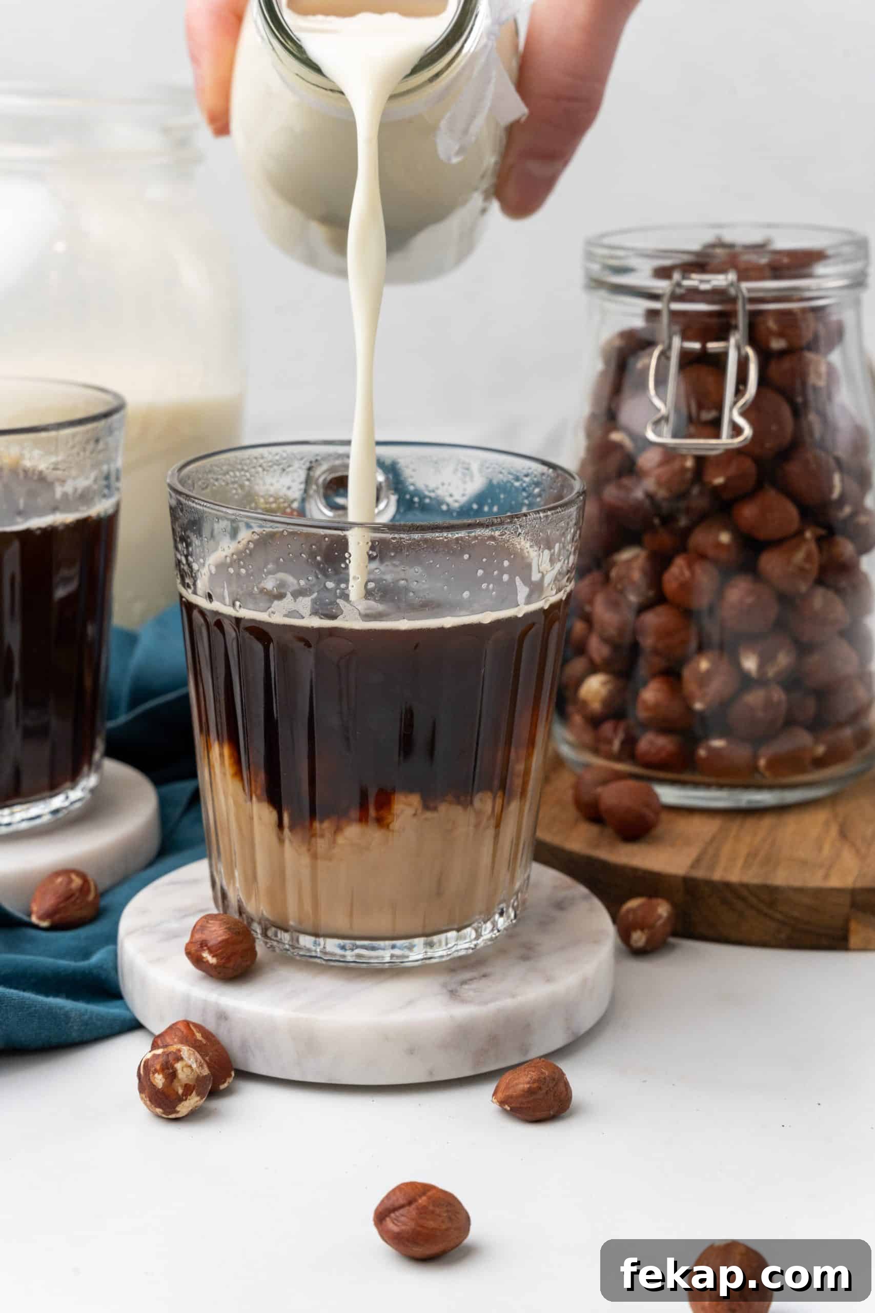 Make Your Own Hazelnut Coffee Creamer 6 homemade hazelnut coffee creamer being poured into a glass mug filled with black coffee