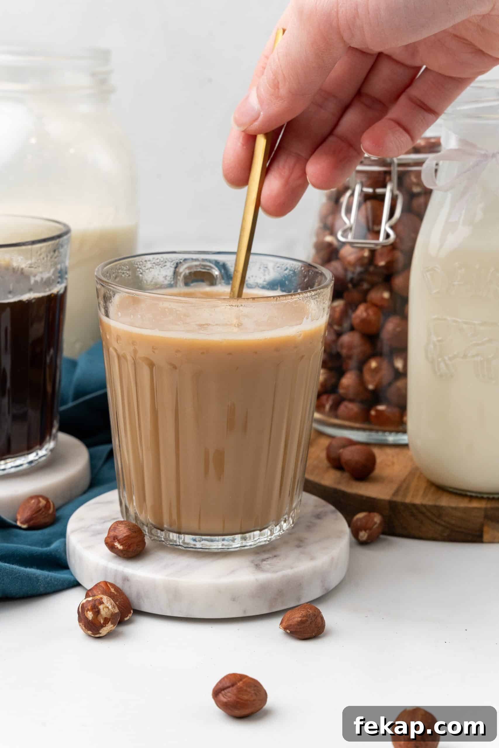 Make Your Own Hazelnut Coffee Creamer 7 a gold spoon stirring coffee and homemade creamer together in a glass mug