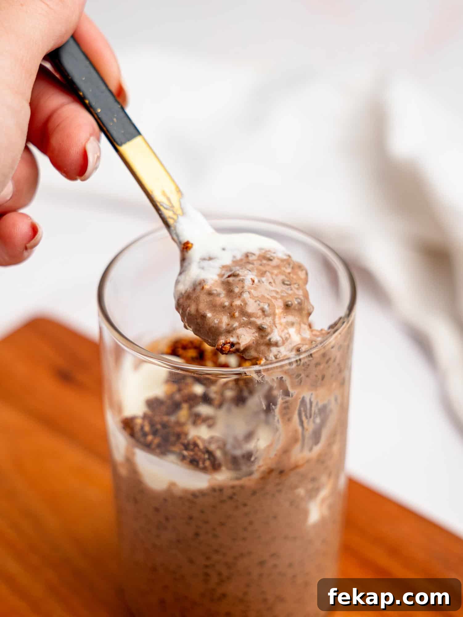 4-Ingredient High-Protein Chia Pudding 2 Chocolate protein chia pudding with yogurt and granola in a glass jar.