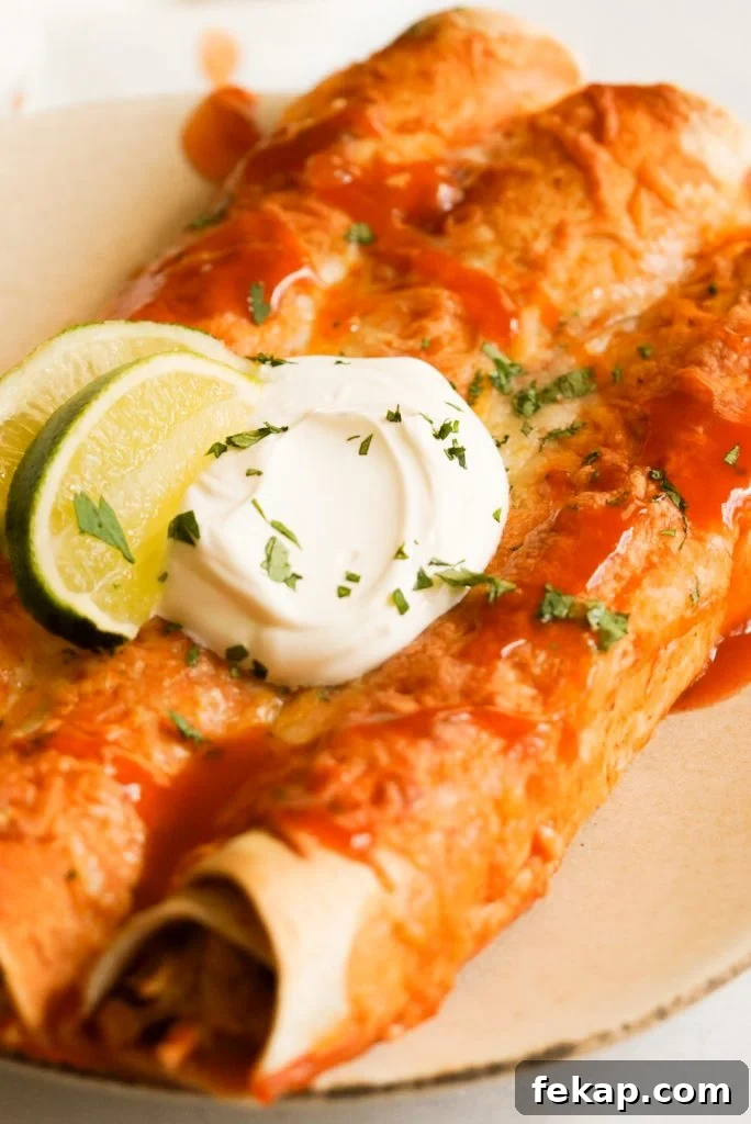 Cheesy Instant Pot Chicken Enchiladas Recipe 3 instant pot enchiladas topped with sour cream, cilantro, and lime juic on a plate