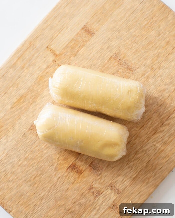 Cut Out Sugar Cookie Recipe for Perfect Shapes 15 Sugar cookie dough wrapped in plastic wrap on a cutting board.