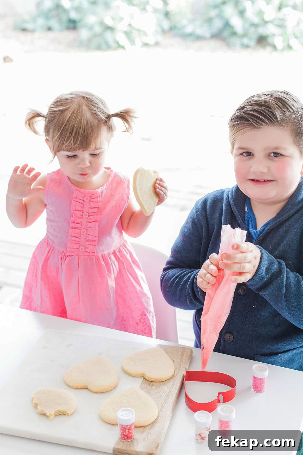 Cut Out Sugar Cookie Recipe for Perfect Shapes 6 Two small children a girl, and a boy decorating heart shaped cookies.