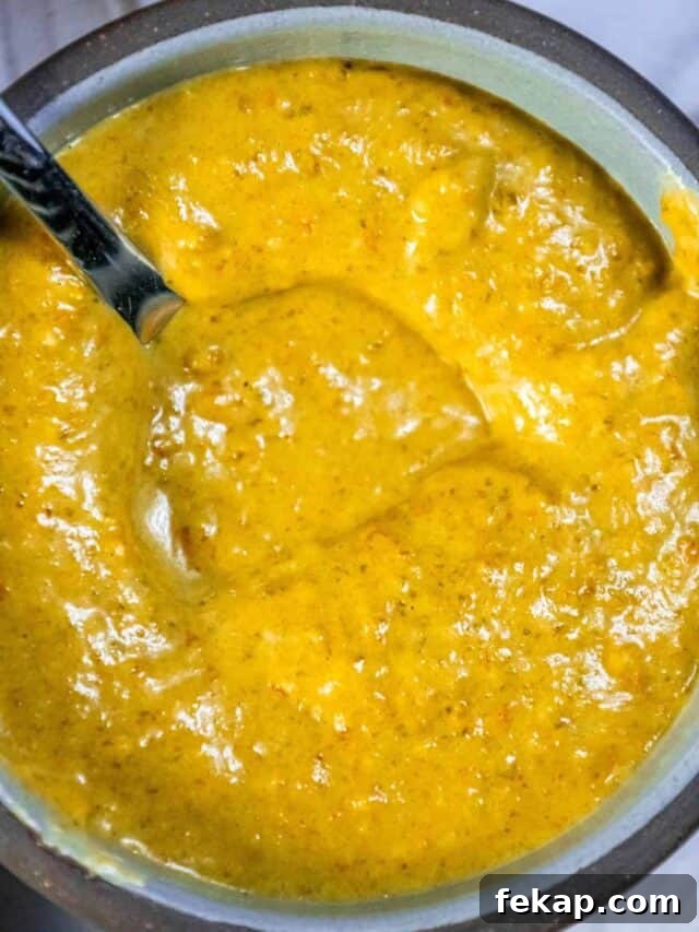 Homemade Habanero Hot Sauce Recipe: Fiery Flavor 2 A bowl of yellow sauce with a spoon in it.