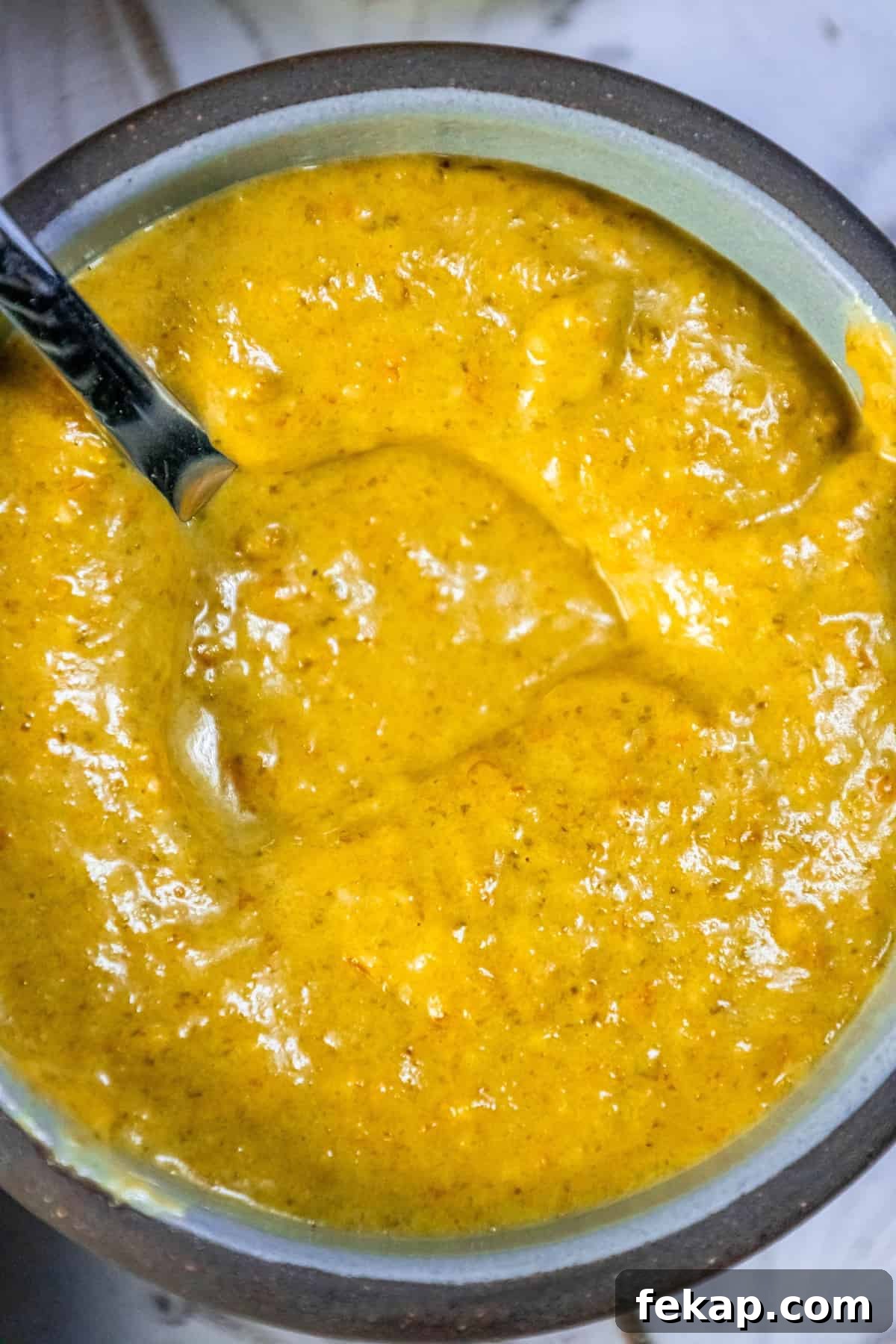Homemade Habanero Hot Sauce Recipe: Fiery Flavor 7 A bowl of yellow habanero sauce with a spoon in it.