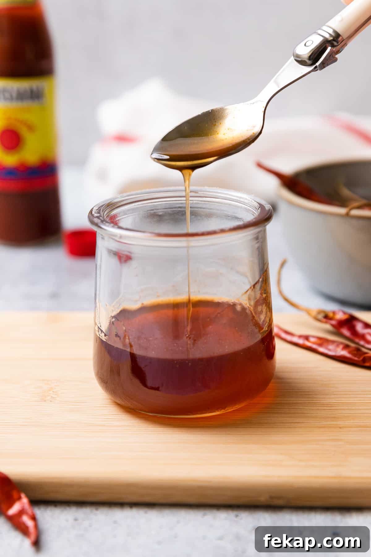 hot honey sauce drizzling off a spoon into a glass jar
