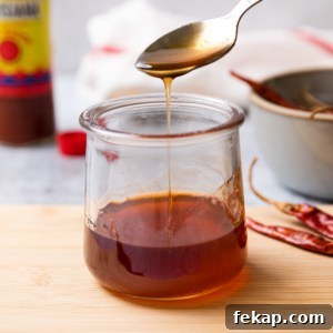 hot honey sauce being drizzling off a spoon into a glass jar